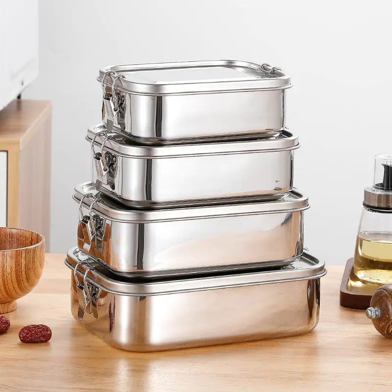 Set of stainless steel lunch boxes on a wooden surface with a white background